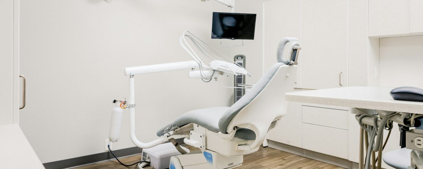 Modern dental treatment room with chair, desk and equipment